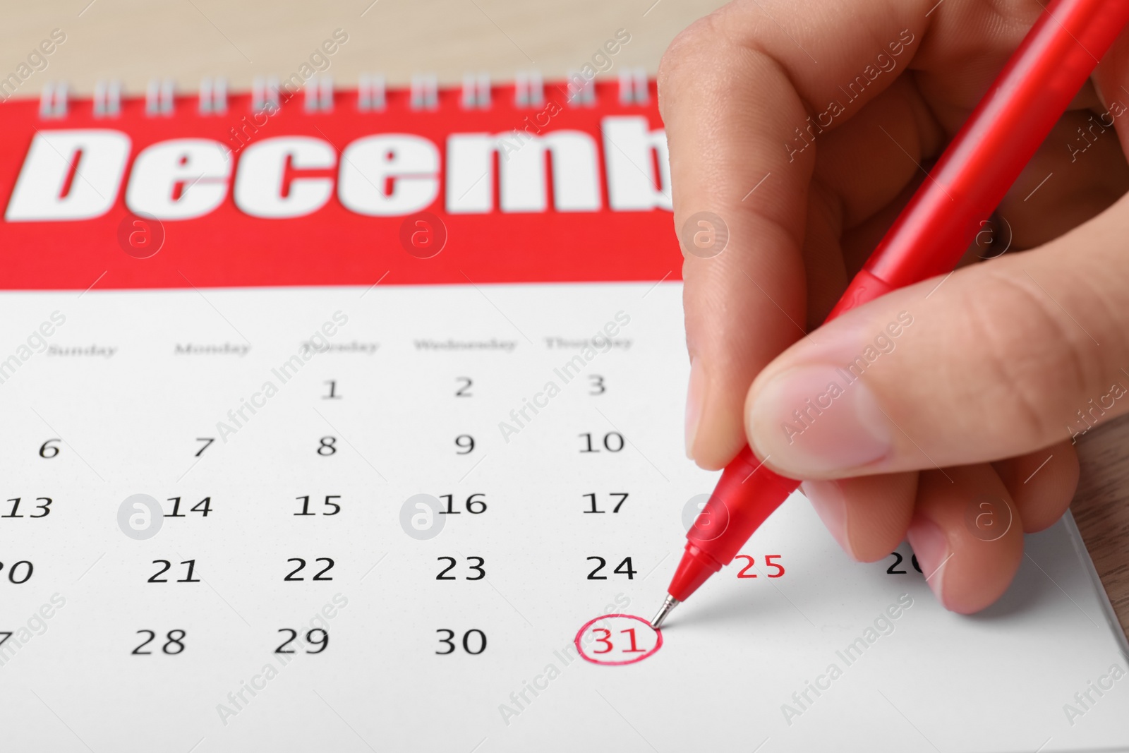 Photo of Woman marking date in calendar at table, closeup. New Year countdown