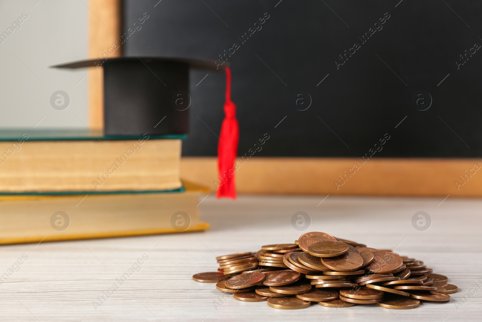 Photo of Scholarship concept. Graduation cap, books and coins on white wooden table