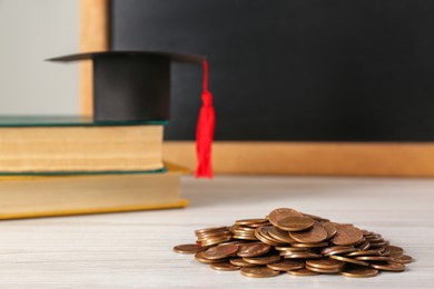 Photo of Scholarship concept. Graduation cap, books and coins on white wooden table