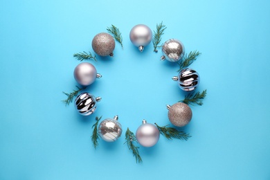 Photo of Bright festive wreath made of Christmas balls and fir branches on light blue background, top view. Space for text