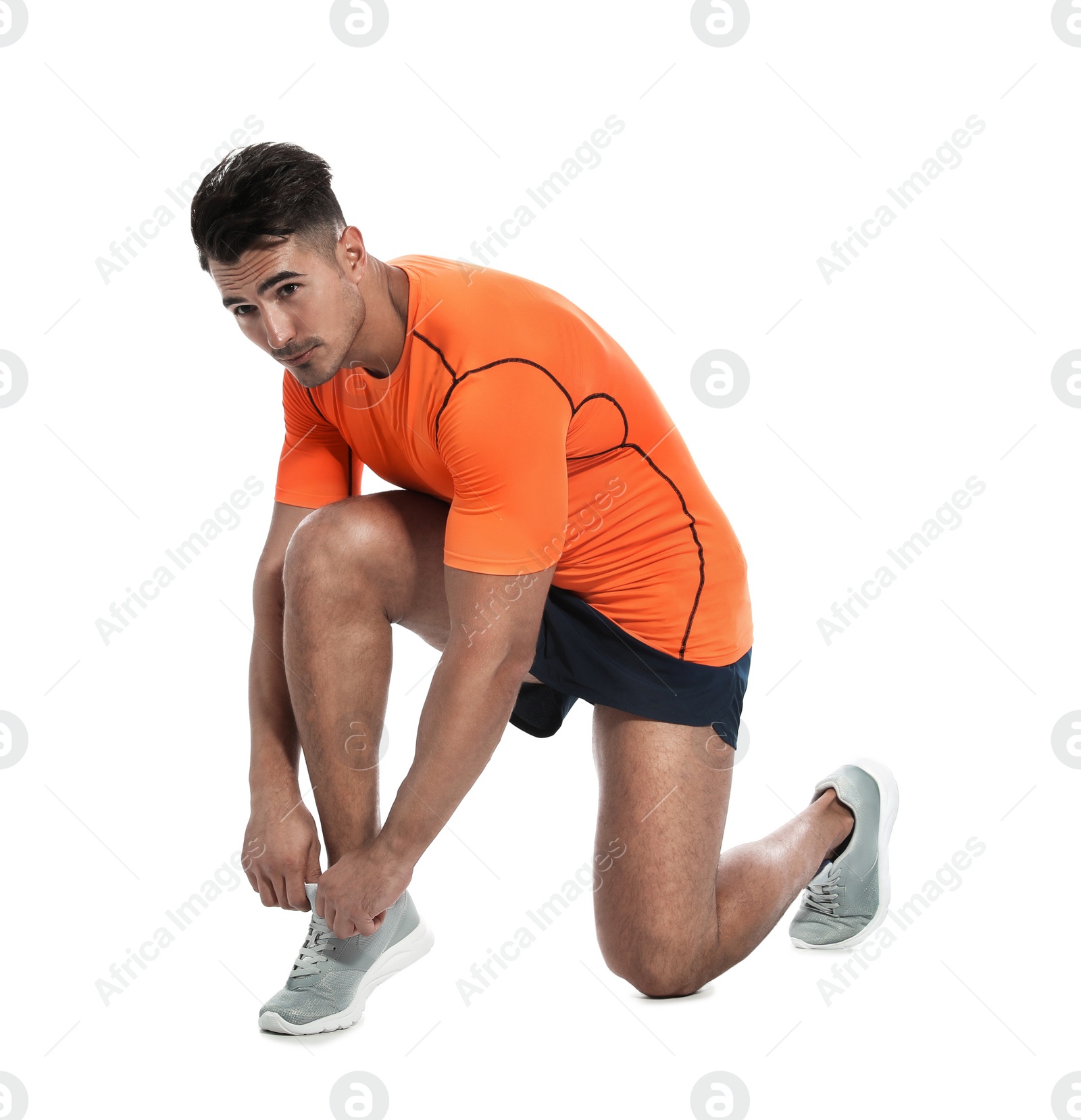 Photo of Handsome young runner tying shoelaces on white background