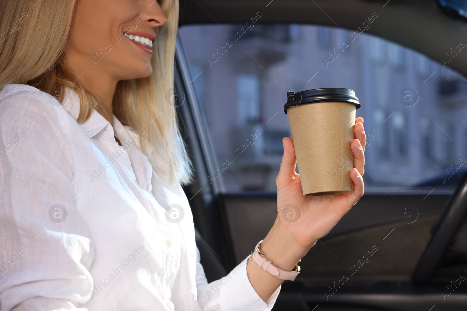 Photo of Coffee to go. Woman with paper cup of drink in car, closeup