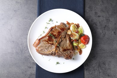 Delicious fried beef meat and vegetables on grey table, top view