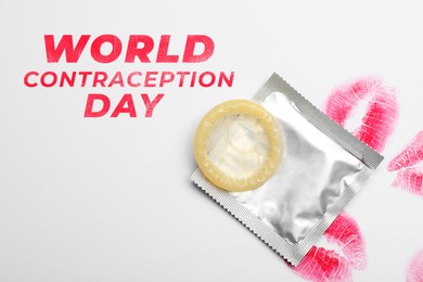 World contraception day. Condom and lipstick kiss marks on white background, top view