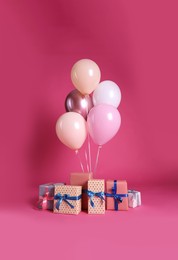 Many gift boxes and balloons near bright pink background