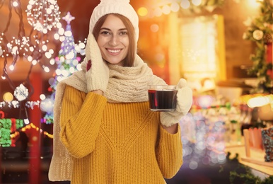 Happy beautiful woman with cup of mulled wine at Christmas fair