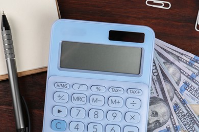 Calculator, notebook, pen and dollar banknotes on wooden table, flat lay. Retirement concept