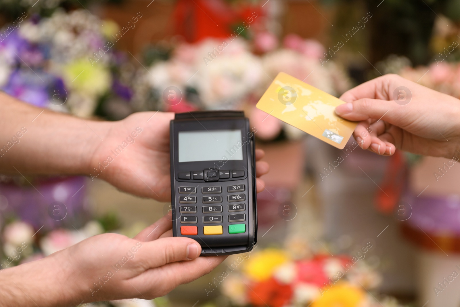 Photo of Woman using credit card for terminal payment in floral shop, closeup