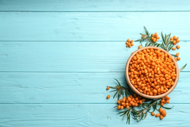 Photo of Fresh ripe sea buckthorn on light blue wooden table, flat lay. Space for text