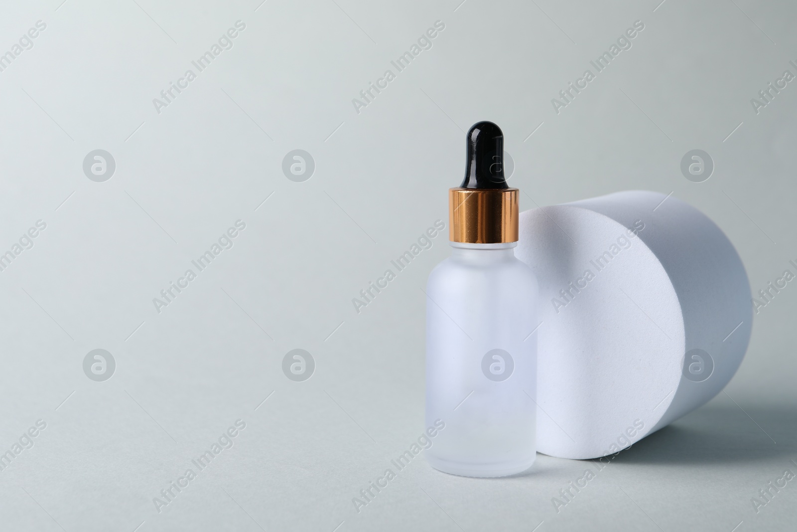 Photo of Bottle with cosmetic serum on light grey background, space for text