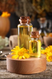 Photo of Bottles of essential oils and calendula flower on wooden table. Medicinal herbs