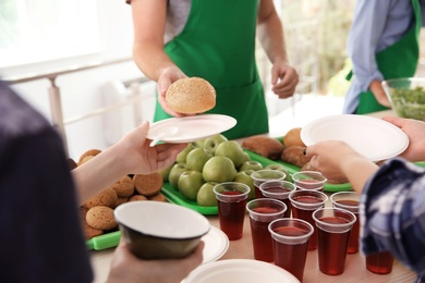 Volunteers serving food for poor people indoors