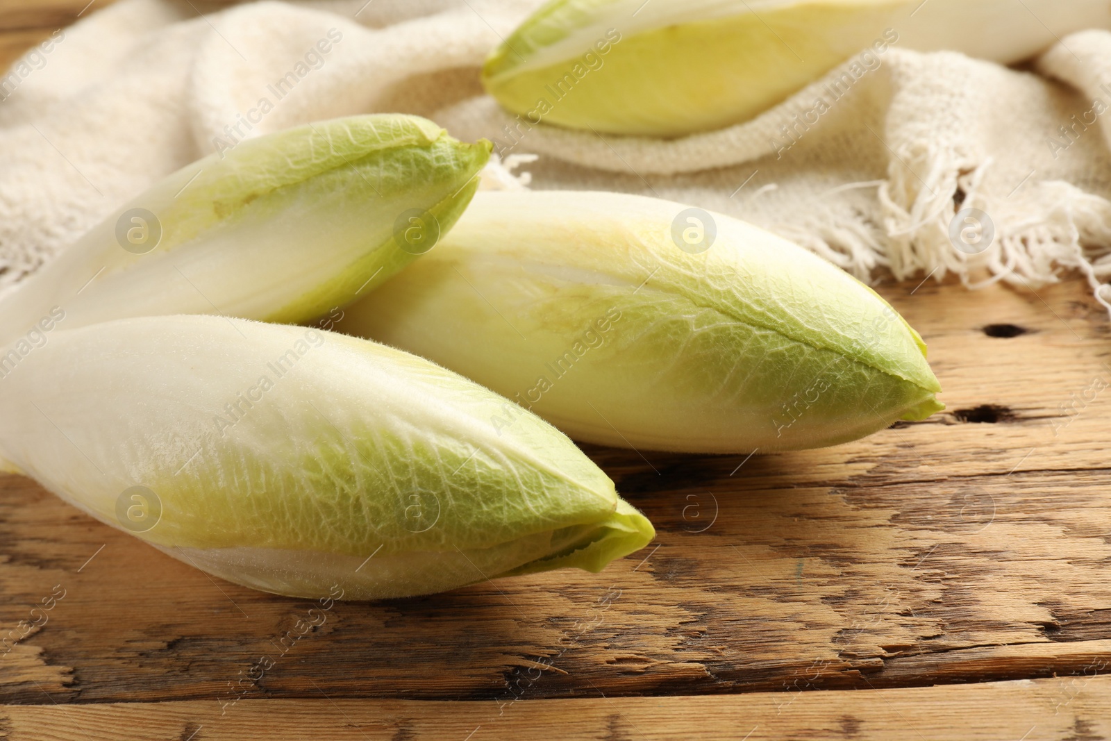 Photo of Fresh raw Belgian endives (chicory) on wooden table, closeup