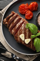 Photo of Delicious grilled beef steak served with spices and tomatoes on table, flat lay