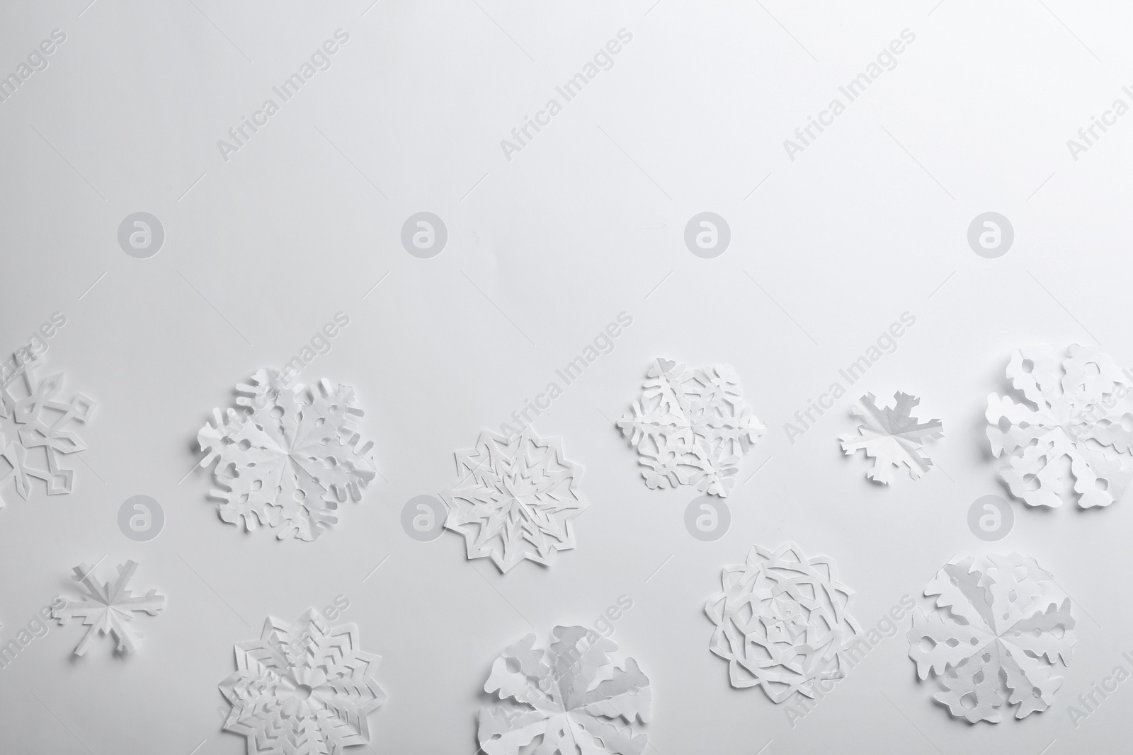 Photo of Many paper snowflakes on white background, flat lay. Space for text