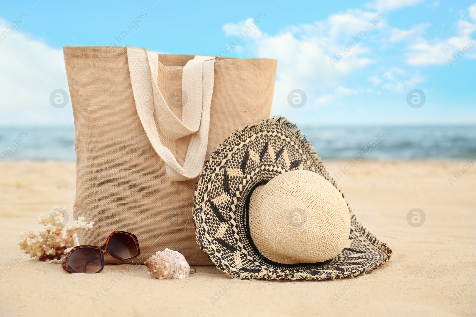 Photo of Different stylish beach objects, coral and seashell on sand near sea