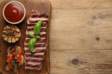 Photo of Delicious grilled beef steak with spices and tomato sauce on wooden table, top view. Space for text