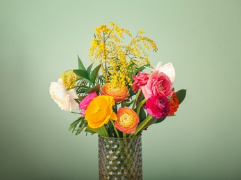 Photo of Vase with beautiful ranunculus flowers on color background