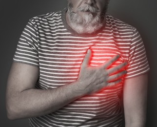 Image of Mature man having heart attack on dark background, closeup view