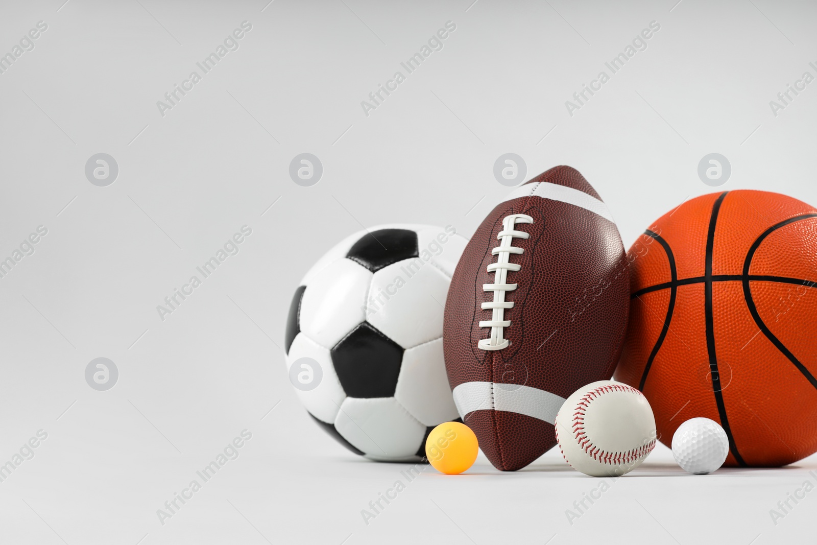 Photo of Many different sports balls on light gray background, space for text
