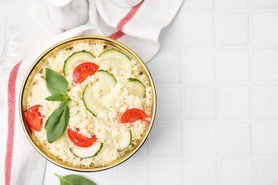 Photo of Tasty couscous with tomatoes, cucumber and basil on white tiled table, flat lay. Space for text