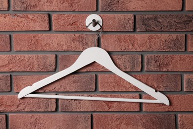 Photo of White clothes hanger on red brick wall