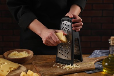 Woman grating cheese at wooden table, closeup