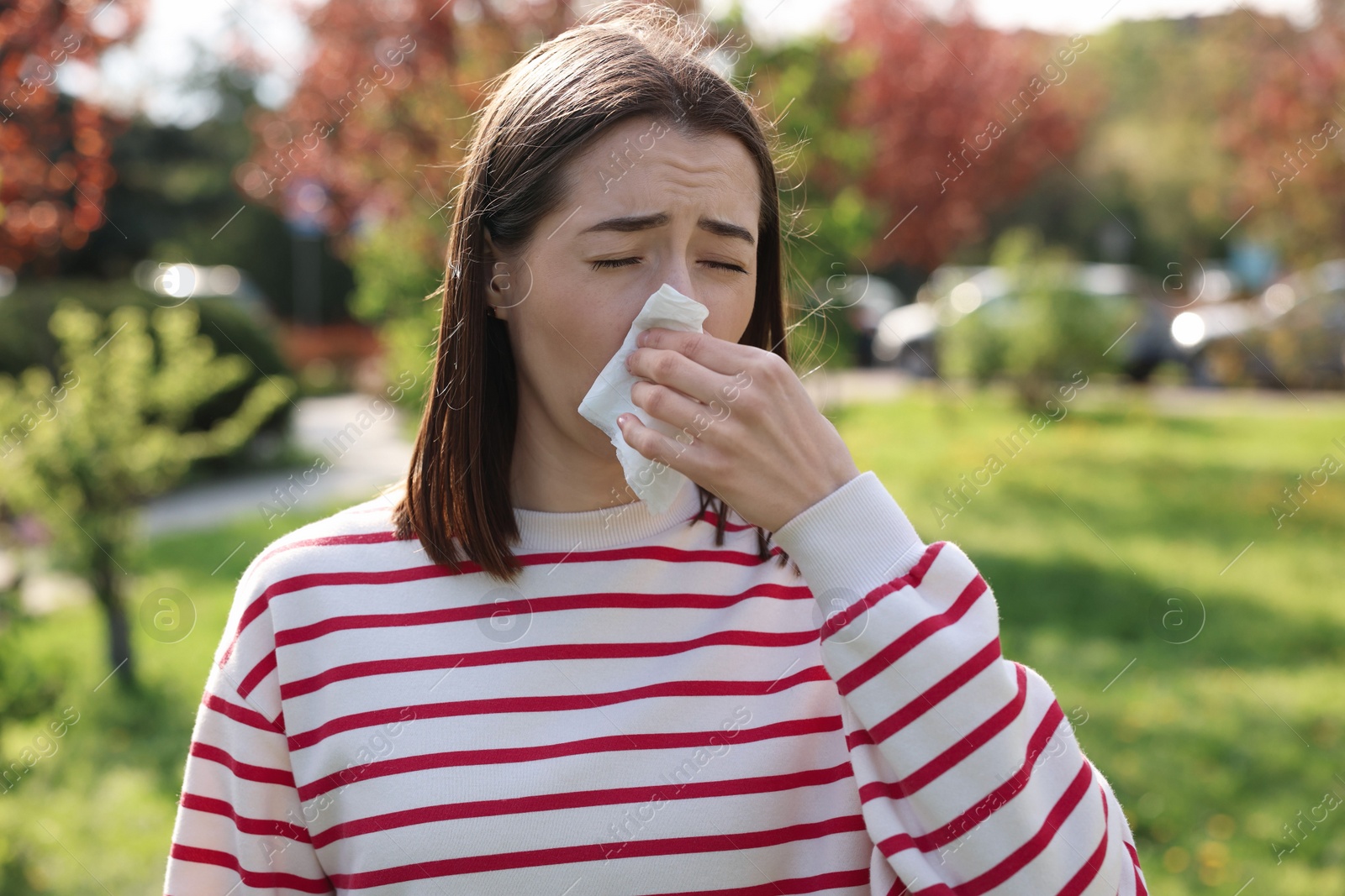 Photo of Woman with napkin suffering from seasonal allergy outdoors