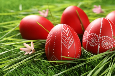 Photo of Red painted Easter eggs on green grass. Space for text