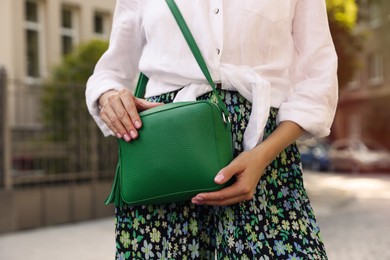 Photo of Woman with stylish green bag on city street, closeup