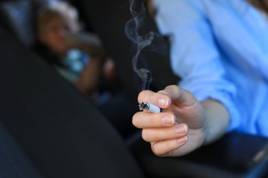 Photo of Mother with cigarette and child in car, closeup. Don't smoke near kids