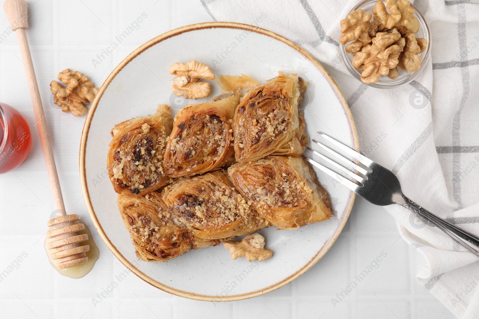 Photo of Eastern sweets. Pieces of tasty baklava on white tiled table, flat lay