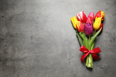 Photo of Beautiful spring tulips on grey stone table, top view. Space for text