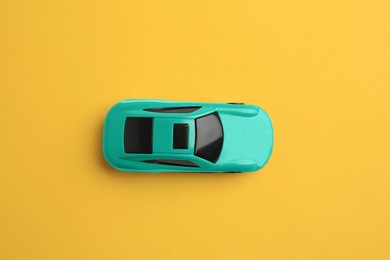 Photo of One turquoise car on yellow background, top view. Children`s toy