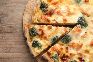 Photo of Delicious homemade quiche with salmon and broccoli on wooden table, top view