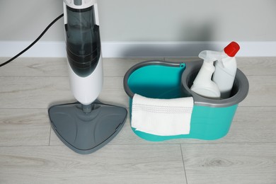 Modern steam mop and bucket with different cleaning supplies on floor, above view