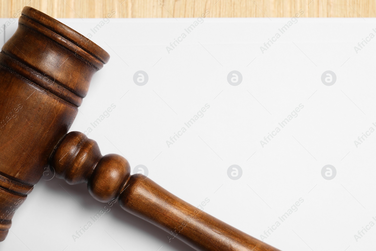 Photo of Law. Blank paper sheet and gavel on table, top view