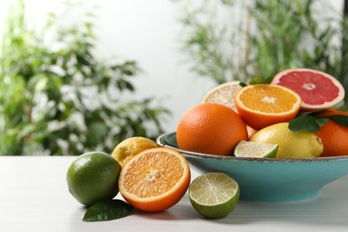 Different cut and whole citrus fruits on white wooden table outdoors