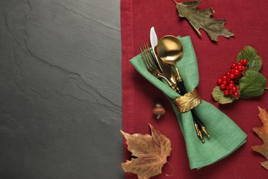 Photo of Autumn table setting. Cutlery, napkins, viburnum berries and leaves on grey textured background, top view with space for text