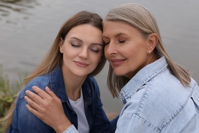 Photo of Happy mature mother and her daughter near pond