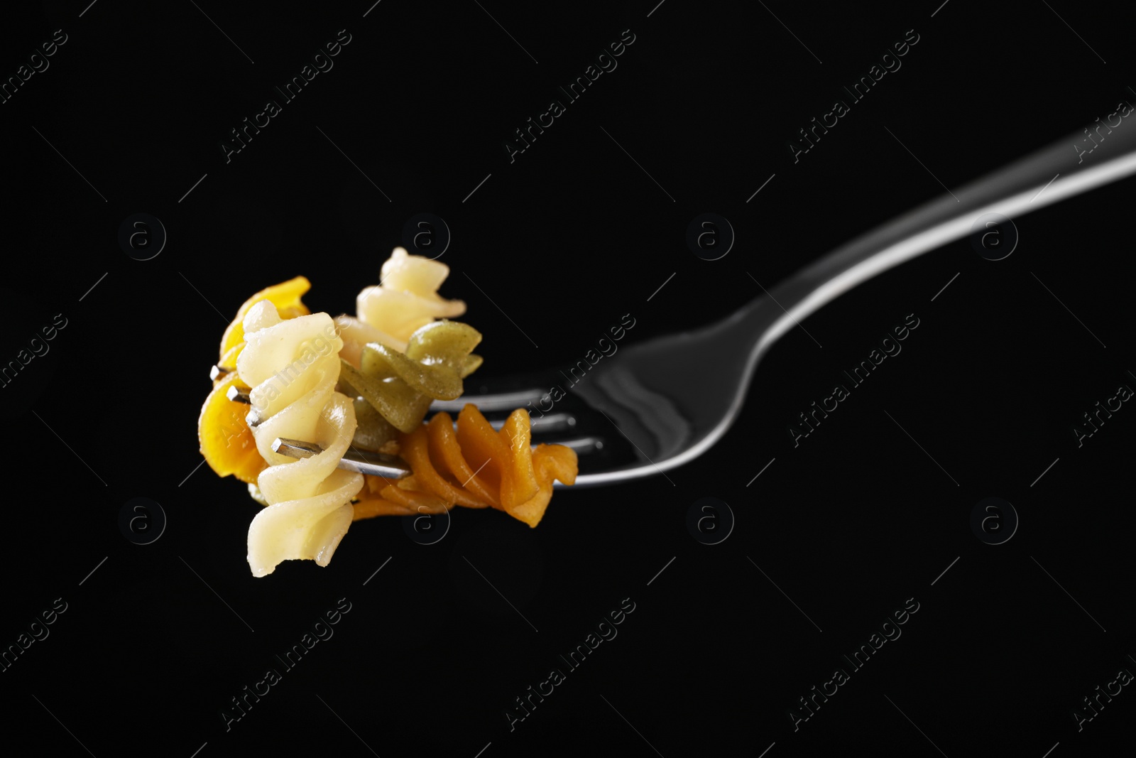 Photo of Fork with delicious spiraline pasta on black background