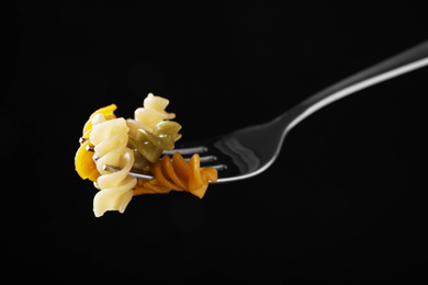 Photo of Fork with delicious spiraline pasta on black background