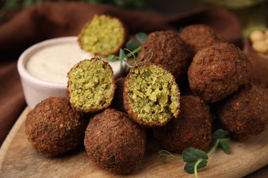 Photo of Delicious falafel balls and sauce on table, closeup