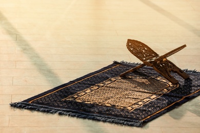 Photo of Rehal on Muslim prayer mat indoors. Space for text