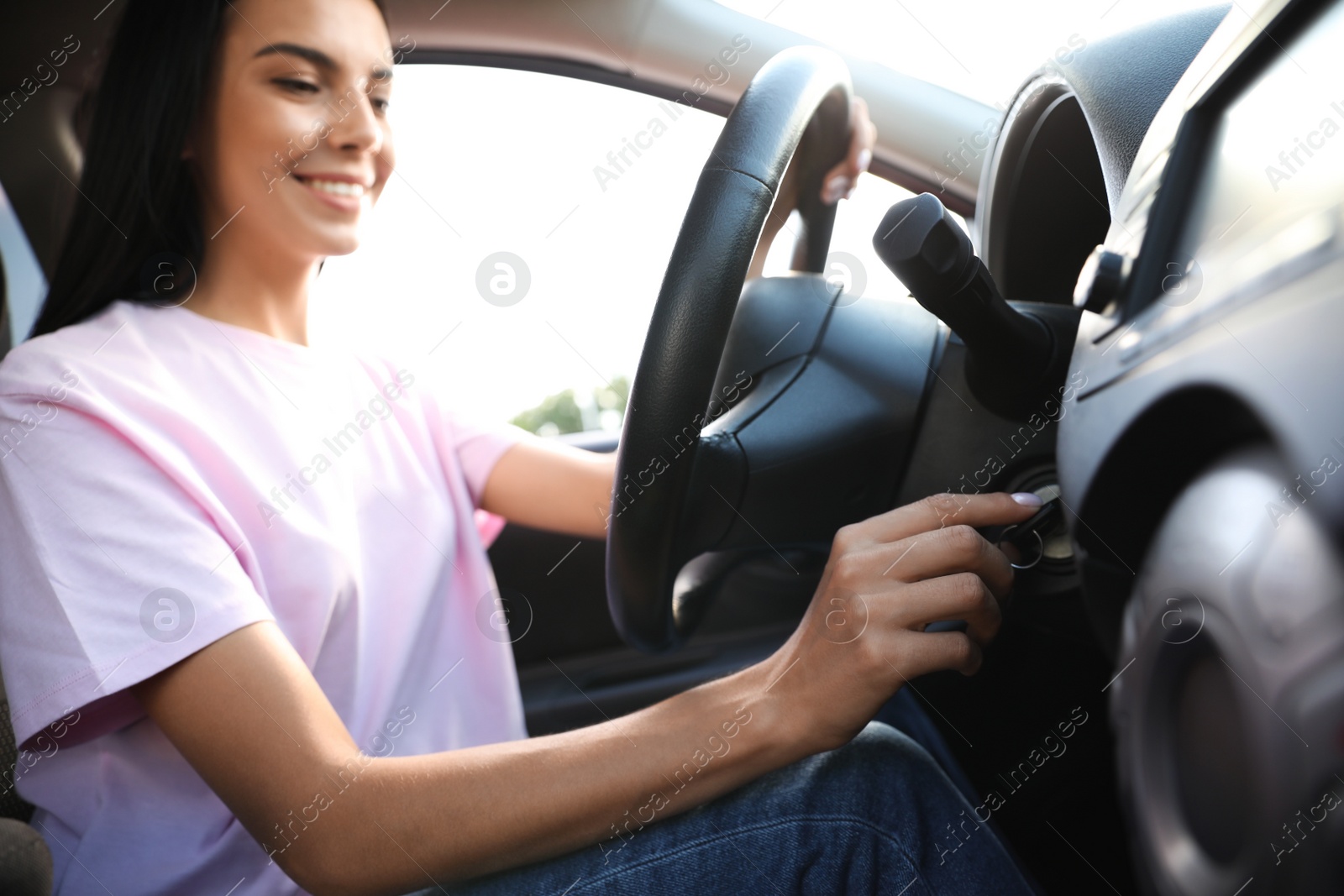 Photo of Young woman starting engine of car. Driving school