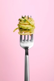 Fork with tasty pasta on pink background