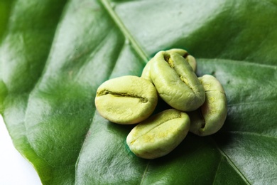 Photo of Green coffee beans on fresh leaf, closeup