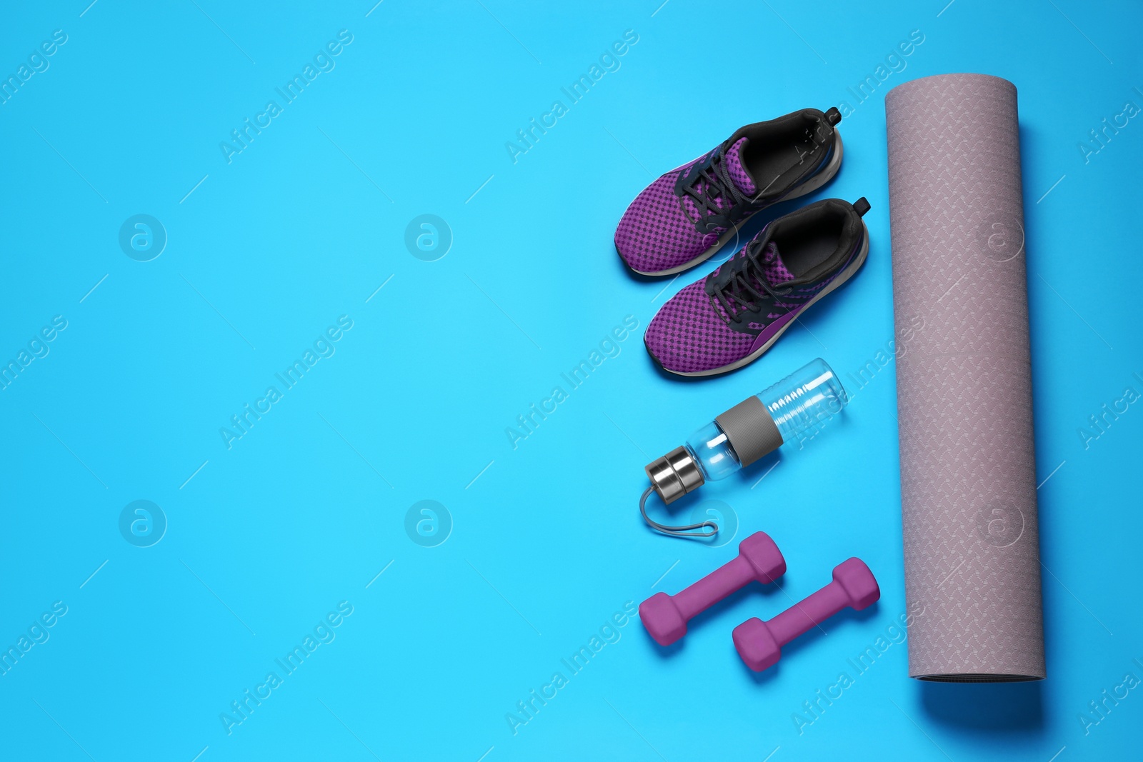 Photo of Exercise mat, dumbbells, bottle of water and shoes on turquoise background, flat lay. Space for text