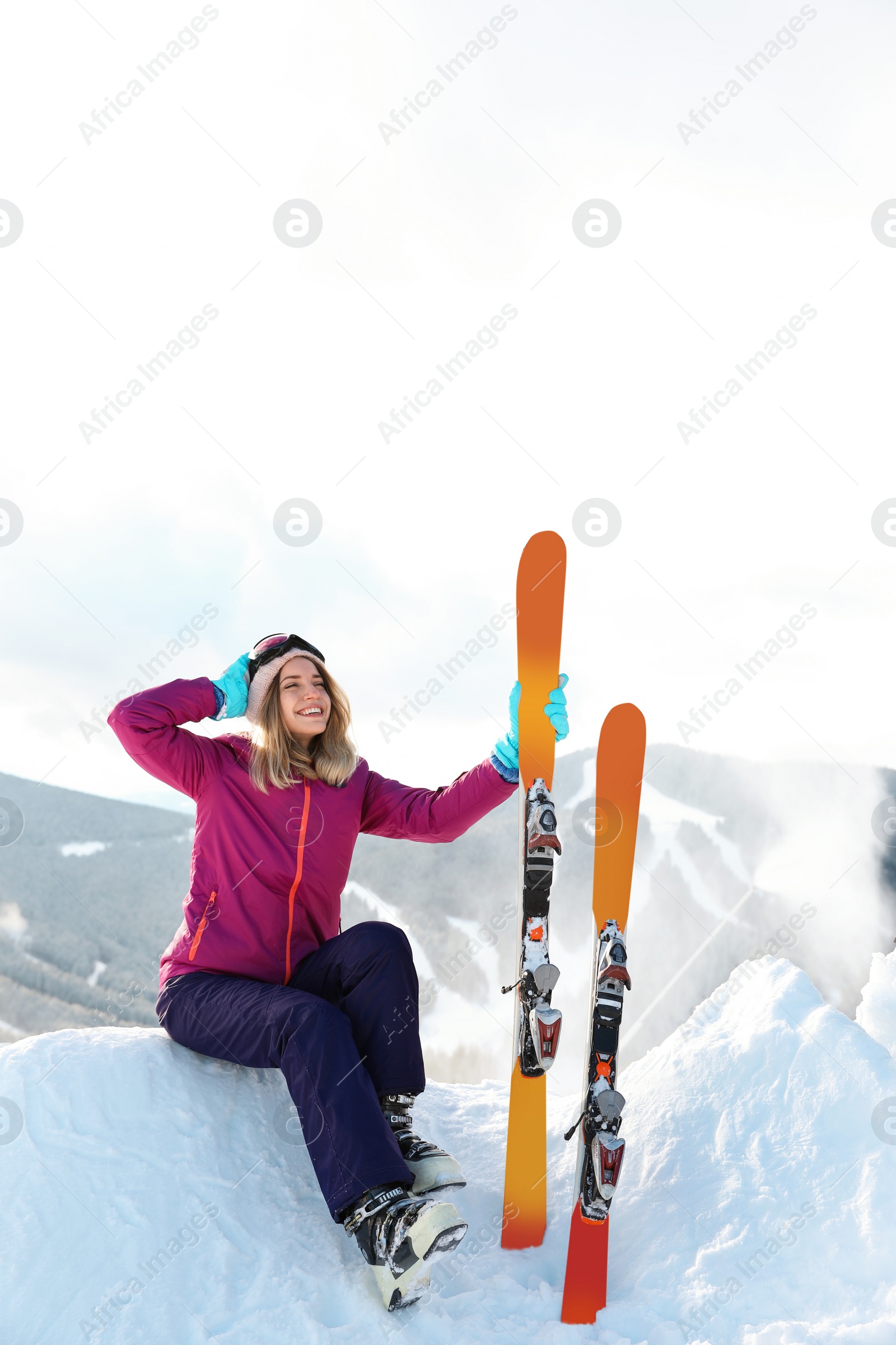 Photo of Young woman with ski equipment sitting on snowdrift in mountains. Winter vacation