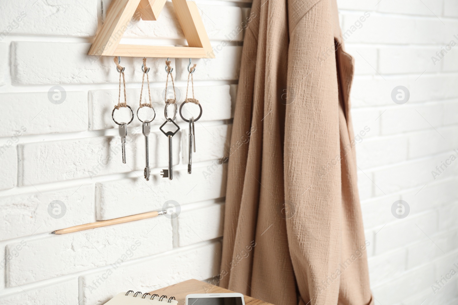 Photo of Wooden key holder on white brick wall indoors